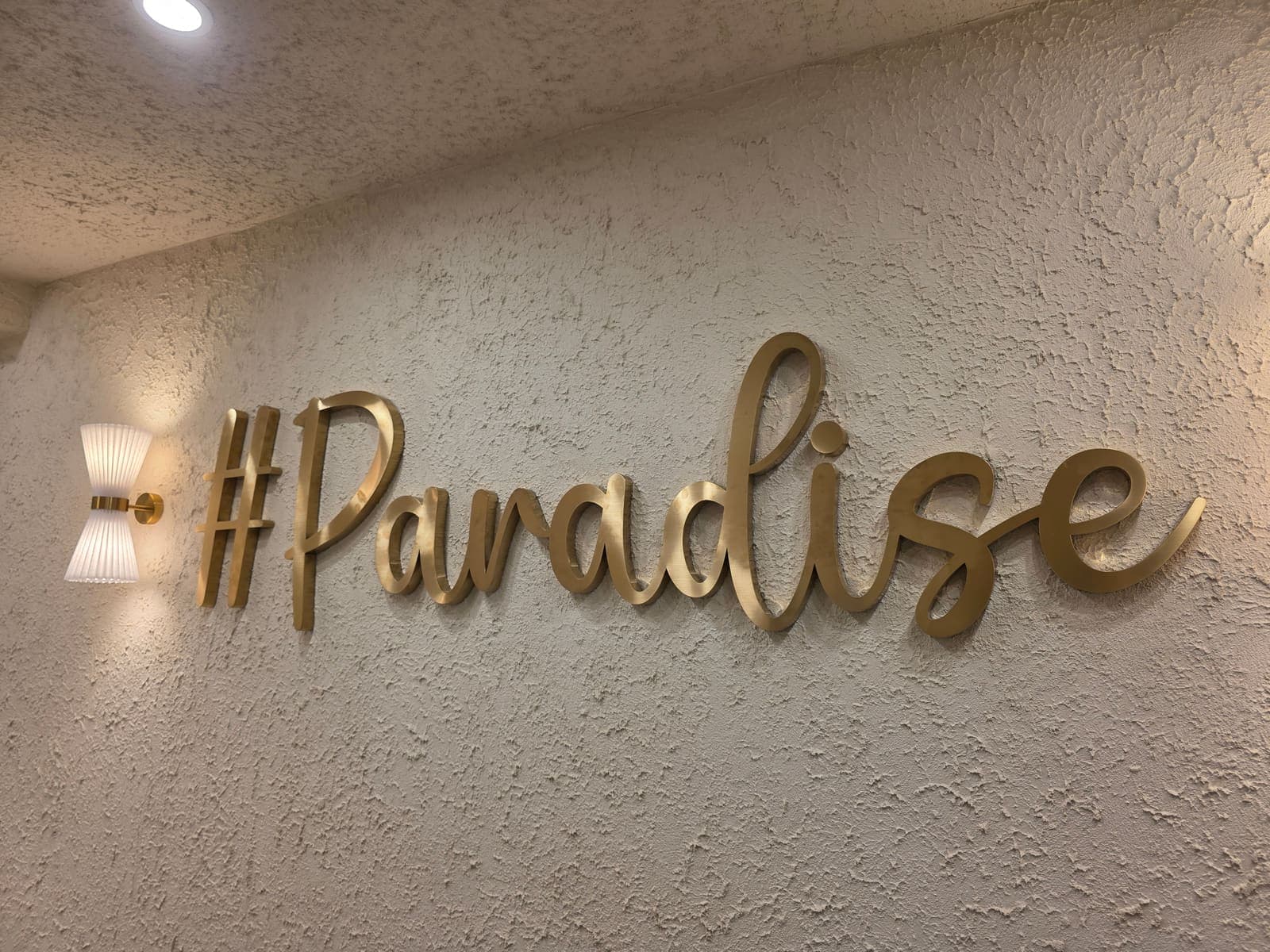 Brushed gold #Paradise sign on the textured feature wall at Paradise Skin Clinic
