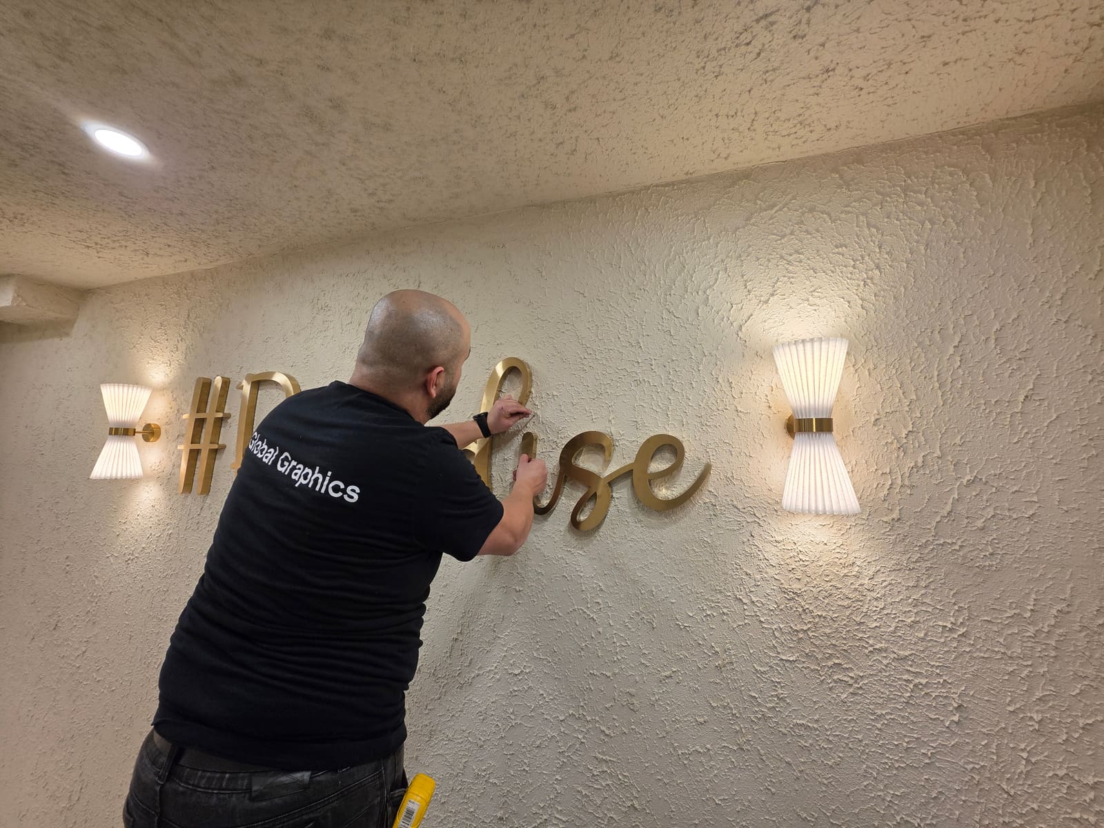 Installing the script lettering between the wall sconces